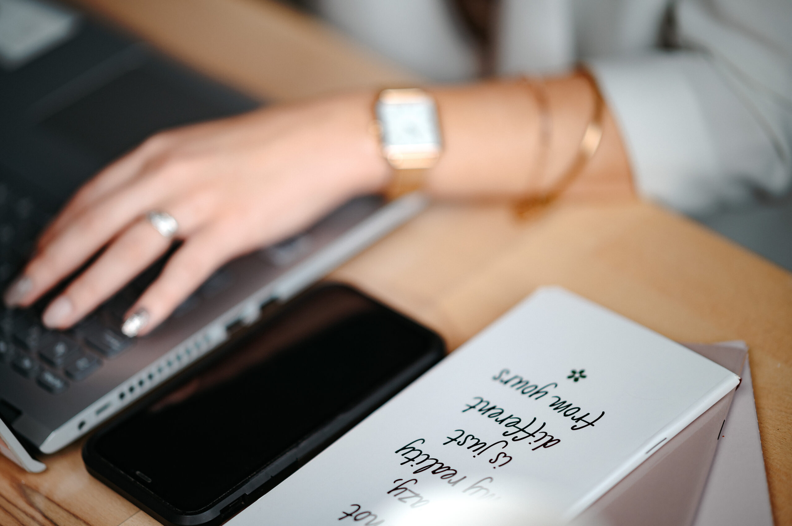 Téléphone éteint à côté d'un ordinateur, symbolisant le manque de contacts, avec une main sur un clavier et un carnet de notes